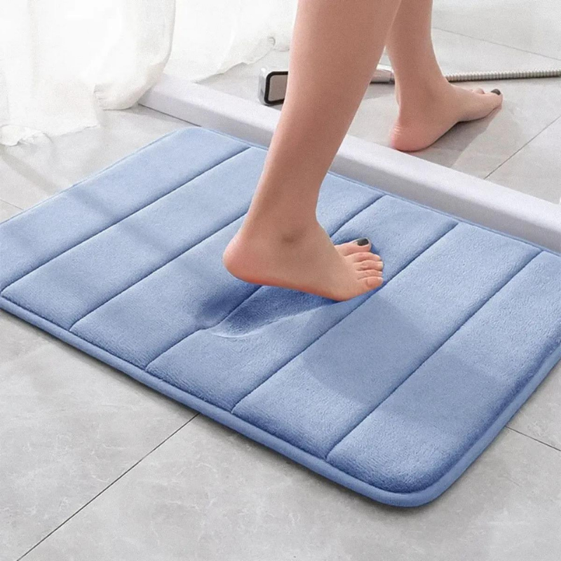 tapete de banheiro soft super absorvente cor azul sendo pisado e espuma com formato do pé da mulher