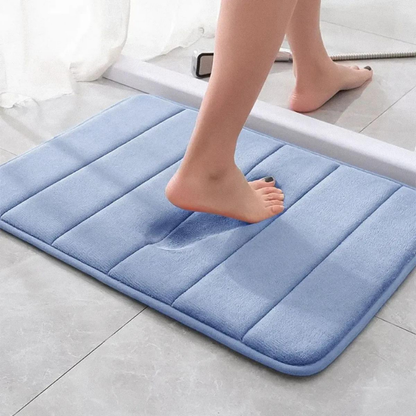 tapete de banheiro soft super absorvente cor azul sendo pisado e espuma com formato do pé da mulher